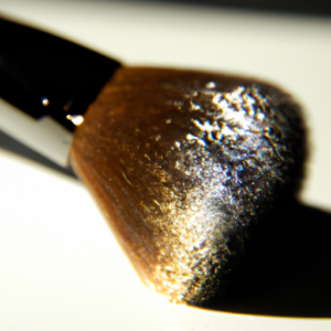 A close-up of a makeup brush with a single shadow shimmering off the bristles.