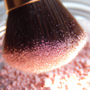 A close-up of a makeup brush with a light pink, shimmery powder.