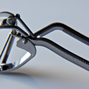 A closeup of a silver eyelash curler, angled to show the curve of the handle.