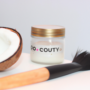 A jar of organic coconut oil with a make-up brush beside it.