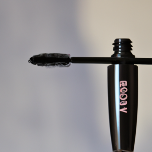 A close up of a tube of mascara with a blurred background.