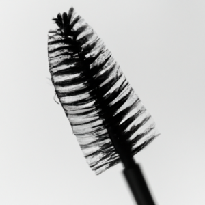 A close-up of a mascara wand with a dramatic, curled, and fluffy lash.