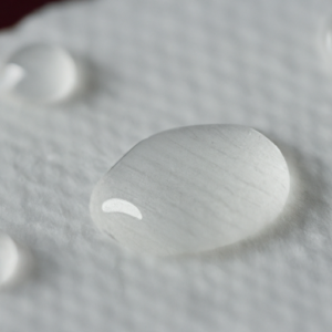 A close-up of a cotton pad with a few drops of liquid on it.