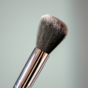 A close-up of a sleek, modern makeup brush with a shimmering metallic handle.