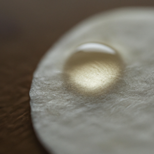 A close-up of a cotton pad with a few drops of natural oil on it.