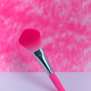 A bright pink makeup brush with a white and pink ombre background.