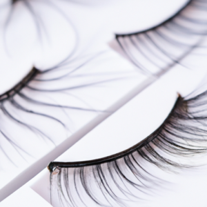 A close-up of a pair of false eyelashes with adhesive on the back.