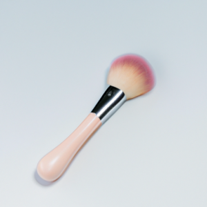 A pastel pink blush brush against a white background.
